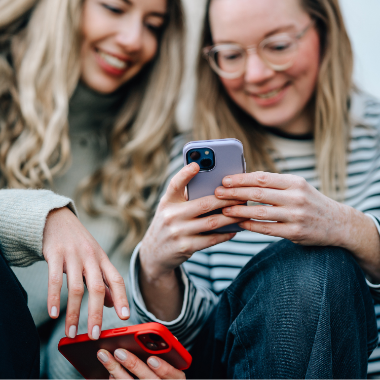 Zwei junge Frauen schauen auf ein Handy