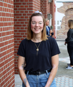 Social Media Managerin Clarissa Niermann Portraitfoto von lächelnder Frau mit heller Brille, blonden Haaren und schwarzem T-Shirt