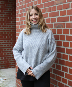 Social Media Managerin Julia De Lon Portraitfoto von Frau mit blonden mittellangen Haaren und grauem Rollkragenpullover