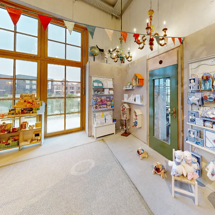 Großer, heller Ausstellungsraum mit Spielwaren und Blick auf einen Fluss.