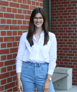 Pressereferentin Fenja Meinshausen Portraitfoto von Frau mit weißer Bluse, brauner Brille und schwarzen längeren Haaren